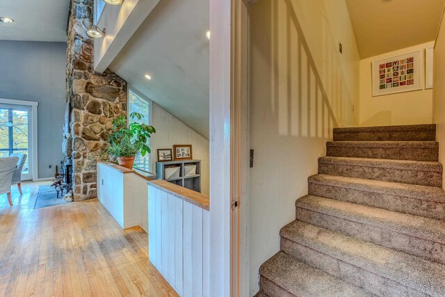 staircase featuring wood-type flooring and high vaulted ceiling