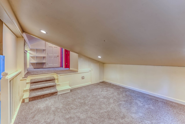 bonus room with light colored carpet and vaulted ceiling