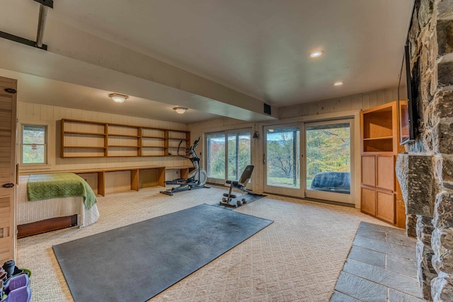 exercise room with light colored carpet and wood walls