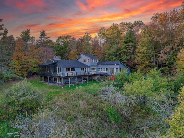 428 Pearl Lake Rd, Sugar Hill, NH 03586 - back of house at dusk featuring a deck, a forest view, and a chimney