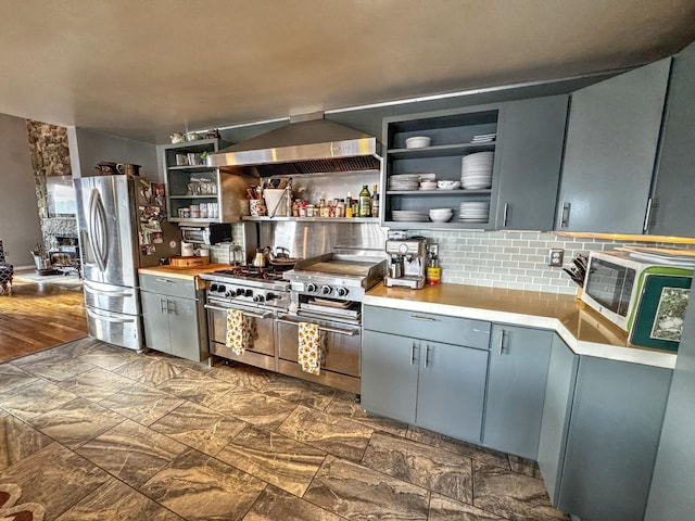 428 Pearl Lake Rd, Sugar Hill, NH 03586 - kitchen featuring wall chimney range hood, stainless steel appliances, open shelves, tasteful backsplash, and light countertops
