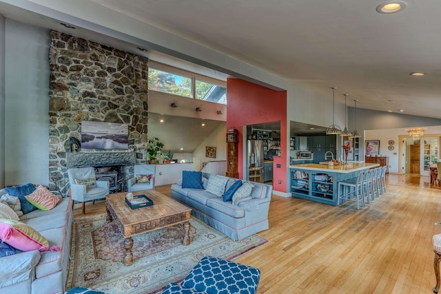 living room with light hardwood / wood-style floors, sink, and high vaulted ceiling