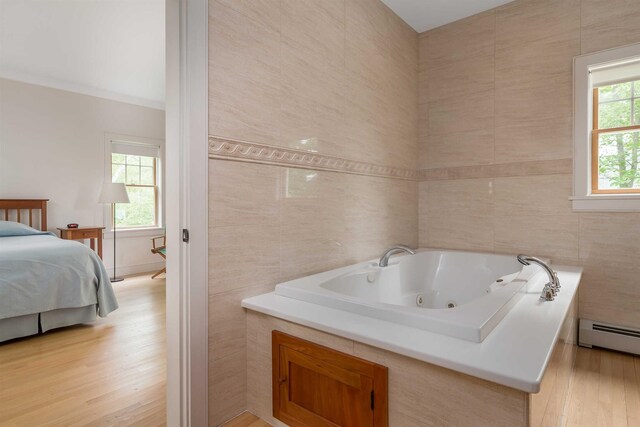 bathroom with tile walls, a bathtub, plenty of natural light, and a baseboard radiator