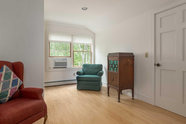 sitting room featuring vaulted ceiling, a baseboard heating unit, cooling unit, and light wood-type flooring