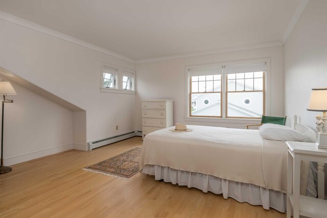 bedroom with a baseboard heating unit, wood-type flooring, and ornamental molding