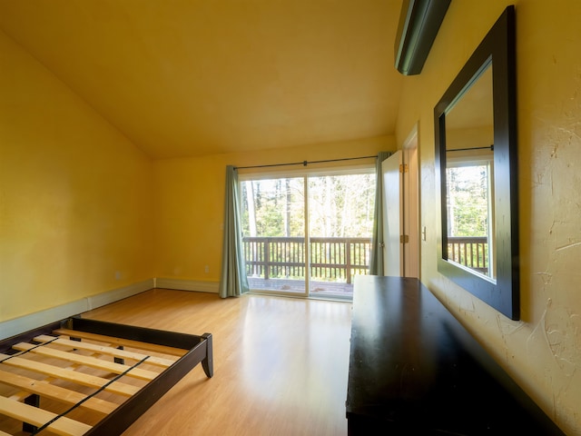 empty room featuring a baseboard radiator, lofted ceiling, and hardwood / wood-style flooring