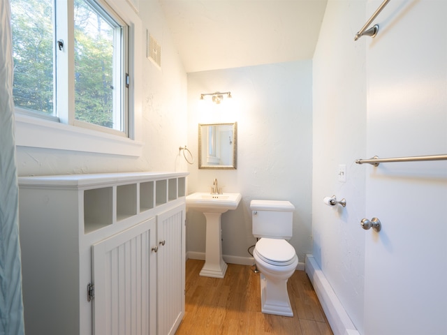 bathroom with wood-type flooring, toilet, and a baseboard heating unit