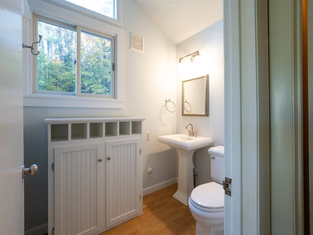 bathroom with wood-type flooring, vaulted ceiling, and toilet