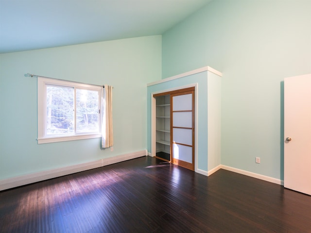 spare room featuring high vaulted ceiling and dark wood-type flooring