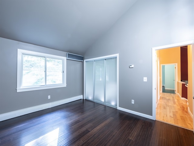 unfurnished bedroom featuring a closet, dark hardwood / wood-style flooring, and high vaulted ceiling