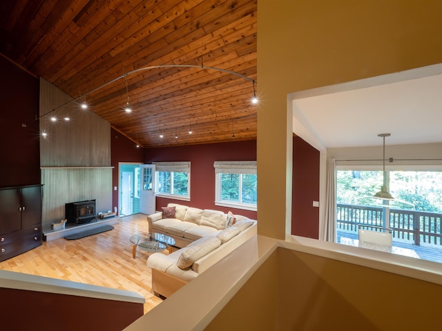 living room with wooden ceiling, a healthy amount of sunlight, lofted ceiling, and a wood stove