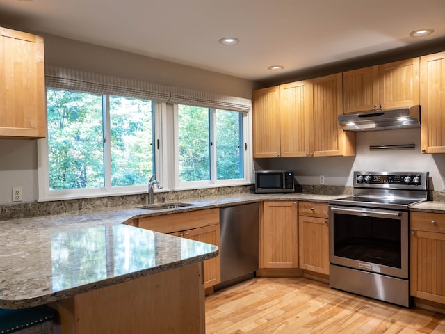 kitchen with light wood-type flooring, kitchen peninsula, appliances with stainless steel finishes, and stone countertops