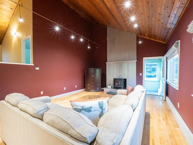 living room with high vaulted ceiling, light wood-type flooring, a wood stove, and wooden ceiling