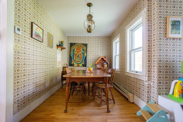 dining space with plenty of natural light, a baseboard heating unit, and light hardwood / wood-style flooring