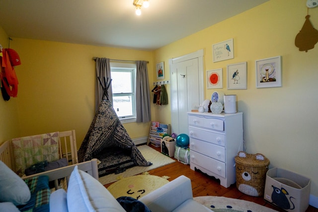 bedroom with dark hardwood / wood-style flooring and a baseboard radiator