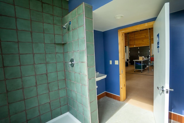 bathroom with concrete floors and tiled shower