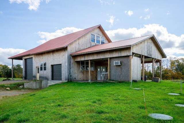 rear view of property featuring a garage, a yard, and an AC wall unit