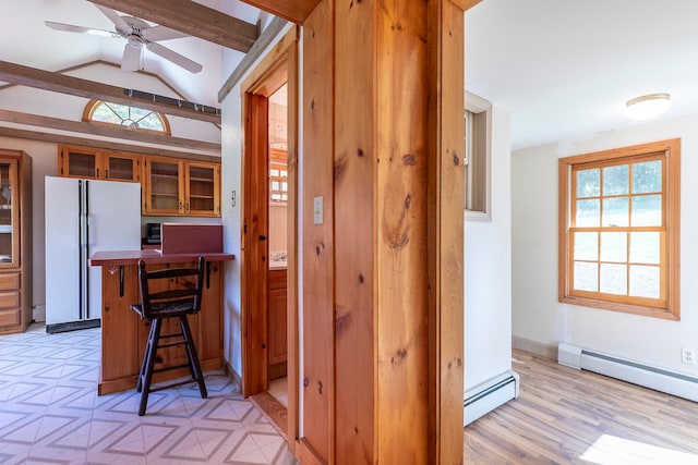 kitchen featuring a kitchen bar, light wood-type flooring, lofted ceiling with beams, a baseboard radiator, and white fridge