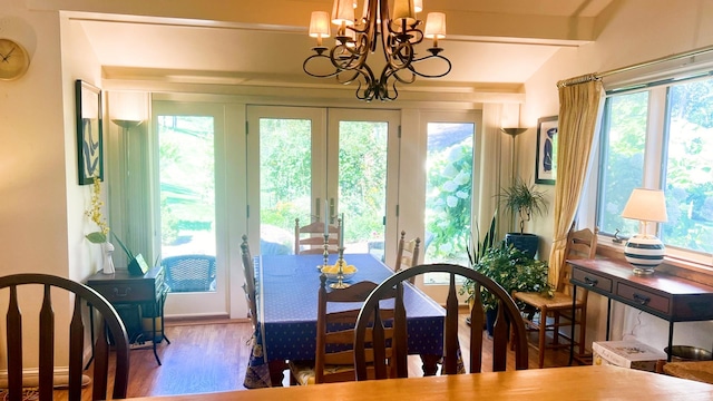 dining space featuring lofted ceiling, wood-type flooring, french doors, and a chandelier