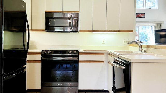 kitchen with appliances with stainless steel finishes, white cabinetry, and sink