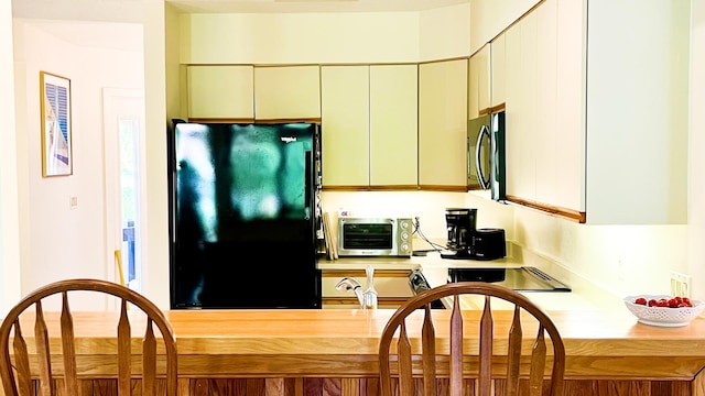 kitchen featuring black fridge and cream cabinetry