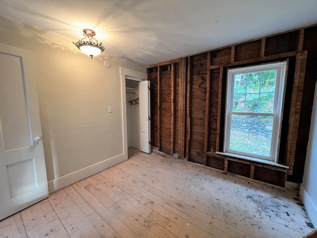 empty room featuring light wood-type flooring and wooden walls