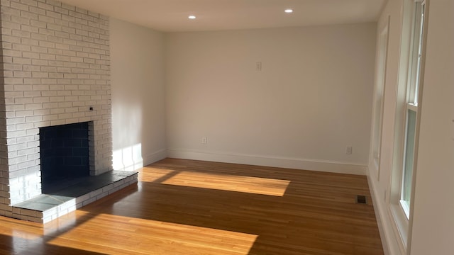 unfurnished living room with a brick fireplace and hardwood / wood-style flooring