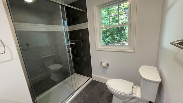 bathroom featuring tile patterned floors, a shower with shower door, and toilet