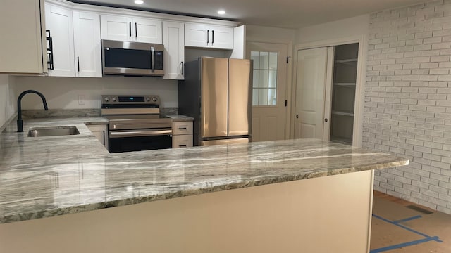 kitchen featuring white cabinets, appliances with stainless steel finishes, sink, and kitchen peninsula