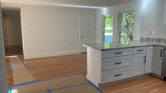 kitchen featuring kitchen peninsula, light hardwood / wood-style flooring, and stone countertops