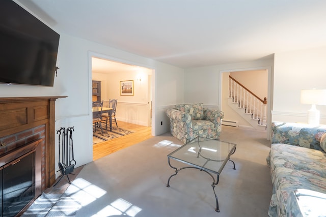 living room featuring baseboard heating, a fireplace, and hardwood / wood-style floors