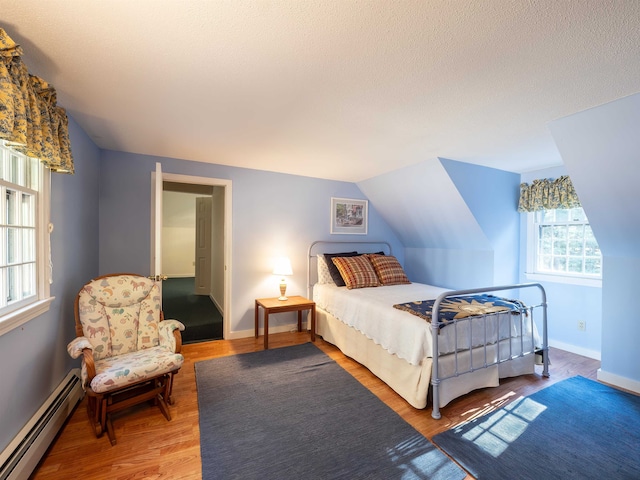 bedroom with lofted ceiling, wood-type flooring, baseboard heating, and multiple windows