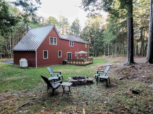 rear view of house with a fire pit, a lawn, and a deck