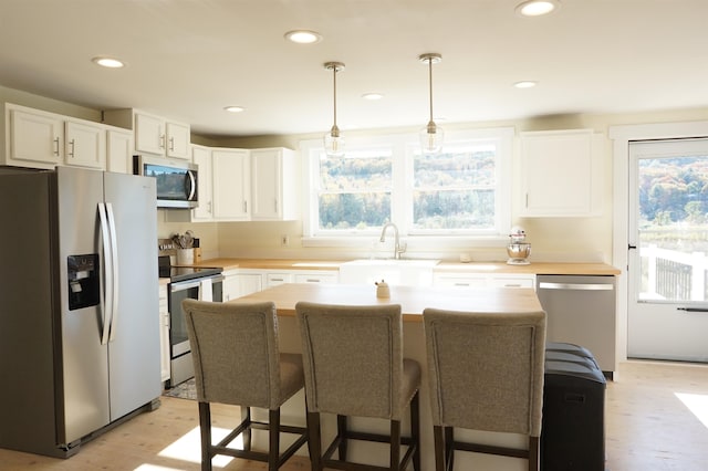 kitchen with white cabinetry, appliances with stainless steel finishes, hanging light fixtures, and plenty of natural light