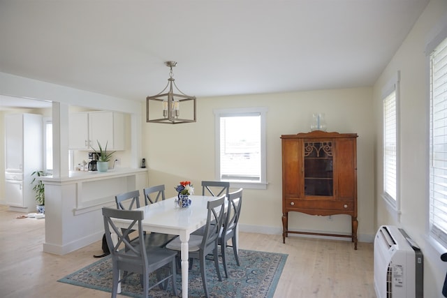 dining space with an inviting chandelier, heating unit, and light wood-type flooring