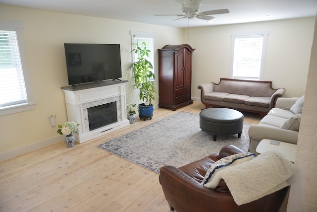 living room with ceiling fan, a fireplace, and light hardwood / wood-style flooring