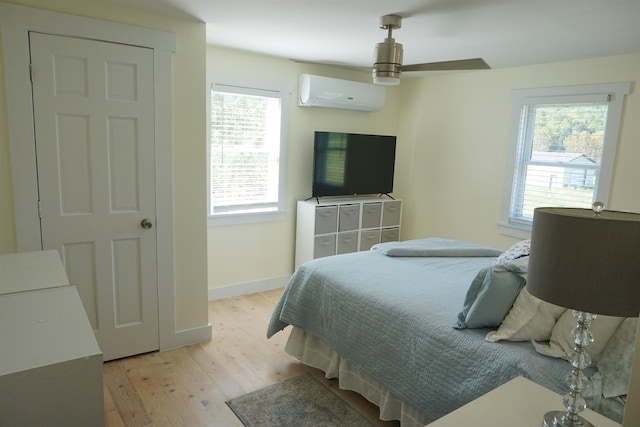 bedroom featuring ceiling fan, a wall unit AC, and light hardwood / wood-style floors