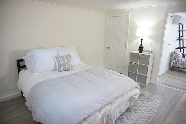 bedroom featuring hardwood / wood-style flooring and an AC wall unit