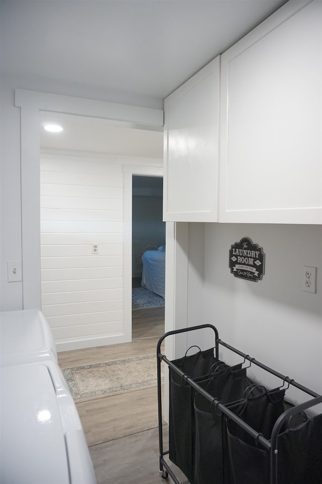 kitchen with white cabinetry, washing machine and clothes dryer, and hardwood / wood-style flooring