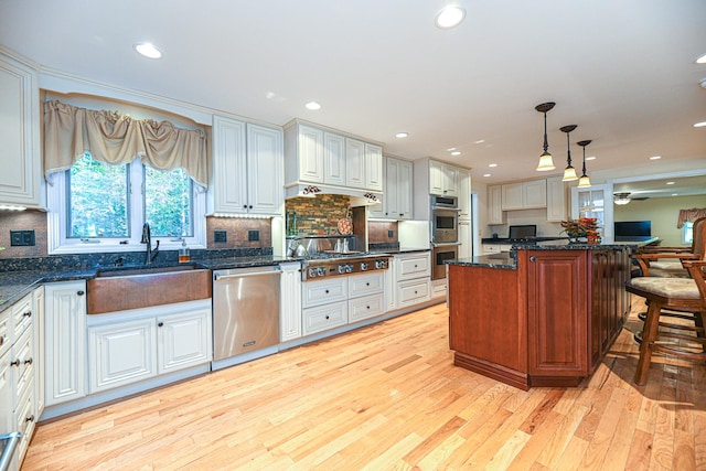 kitchen featuring pendant lighting, light hardwood / wood-style flooring, stainless steel appliances, and white cabinets