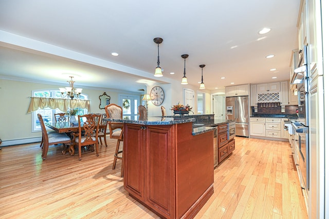 kitchen with a kitchen island with sink, pendant lighting, light hardwood / wood-style flooring, stainless steel fridge with ice dispenser, and a kitchen bar