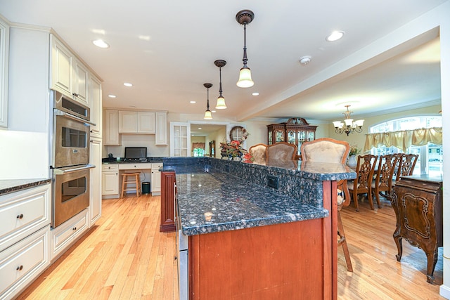 kitchen with hanging light fixtures, light hardwood / wood-style floors, a breakfast bar area, and a kitchen island