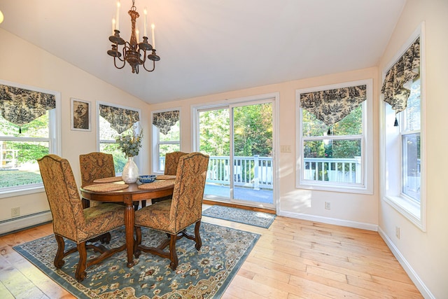 dining area with light hardwood / wood-style floors, vaulted ceiling, a notable chandelier, and a healthy amount of sunlight