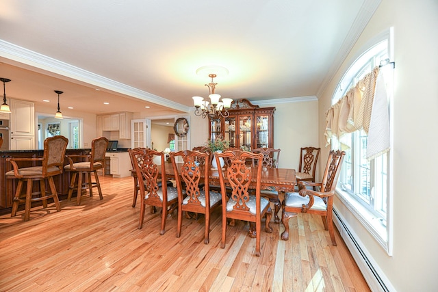 dining area with light hardwood / wood-style flooring, a chandelier, ornamental molding, and a baseboard heating unit