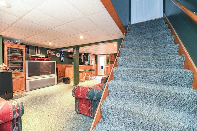 stairway featuring a drop ceiling and carpet flooring