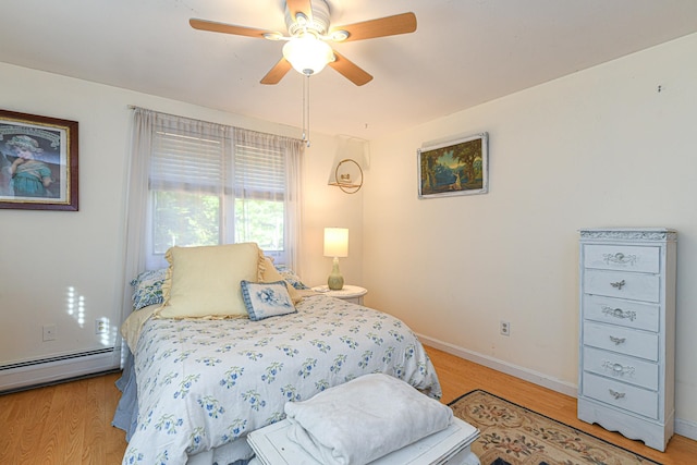 bedroom featuring ceiling fan, light hardwood / wood-style floors, and a baseboard heating unit