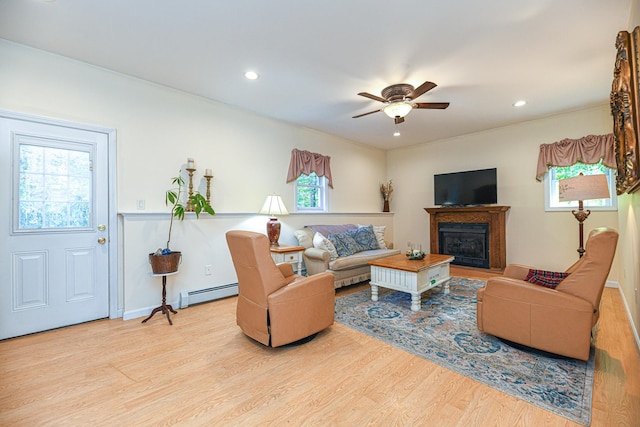 living room featuring a wealth of natural light, a baseboard radiator, and light hardwood / wood-style flooring