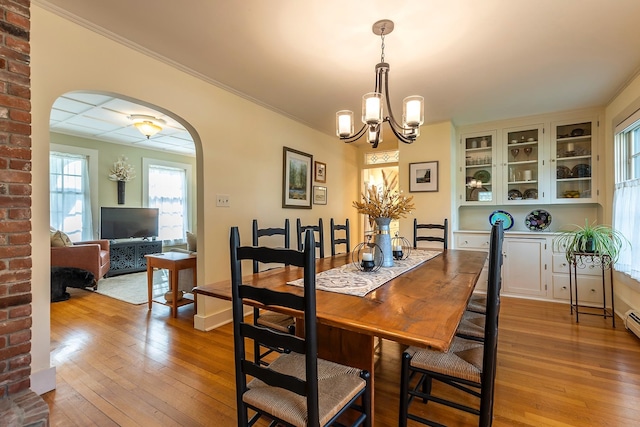 dining space with light hardwood / wood-style floors, crown molding, and a notable chandelier