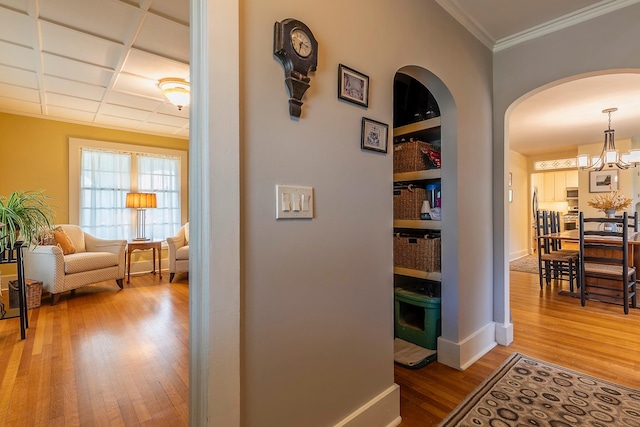 corridor with wood-type flooring, an inviting chandelier, and crown molding