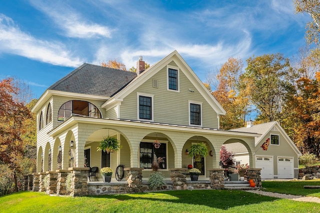 view of front of property featuring a front yard, a garage, a balcony, and covered porch